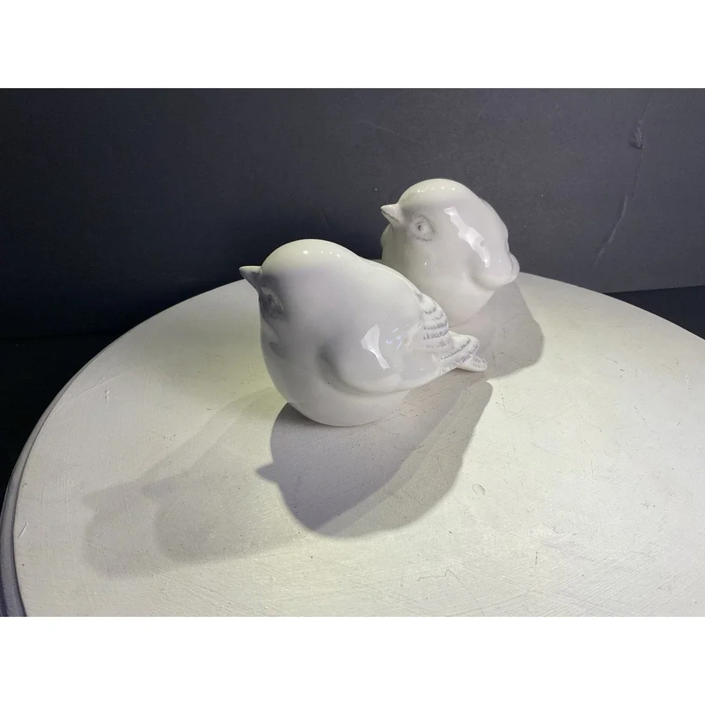 Two little bird figurines with some coloring on the feathers